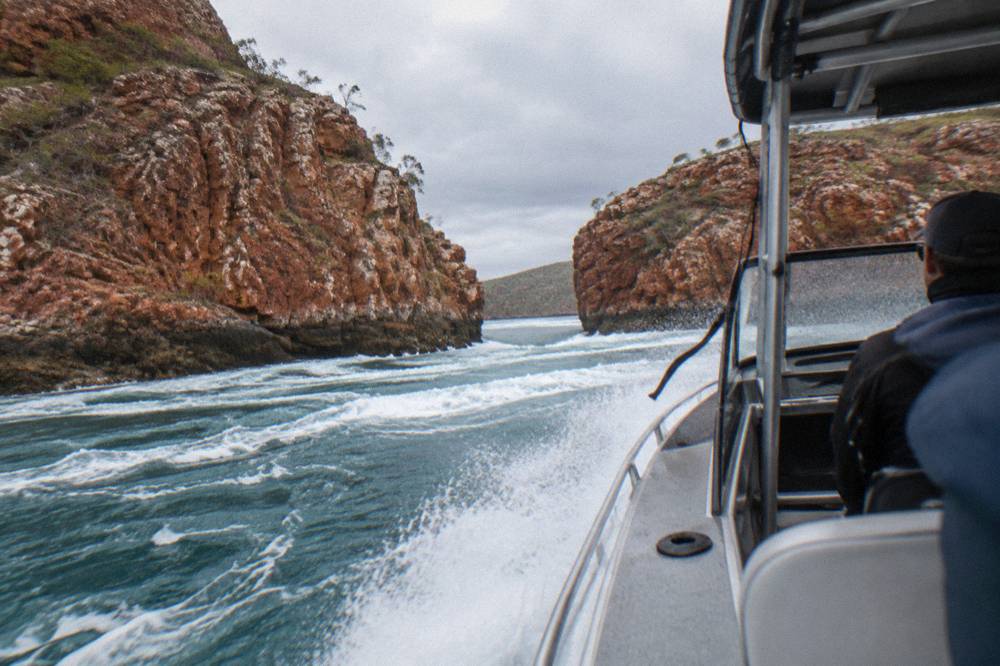 A power boat cutting through white turbulent water between steep rock walls