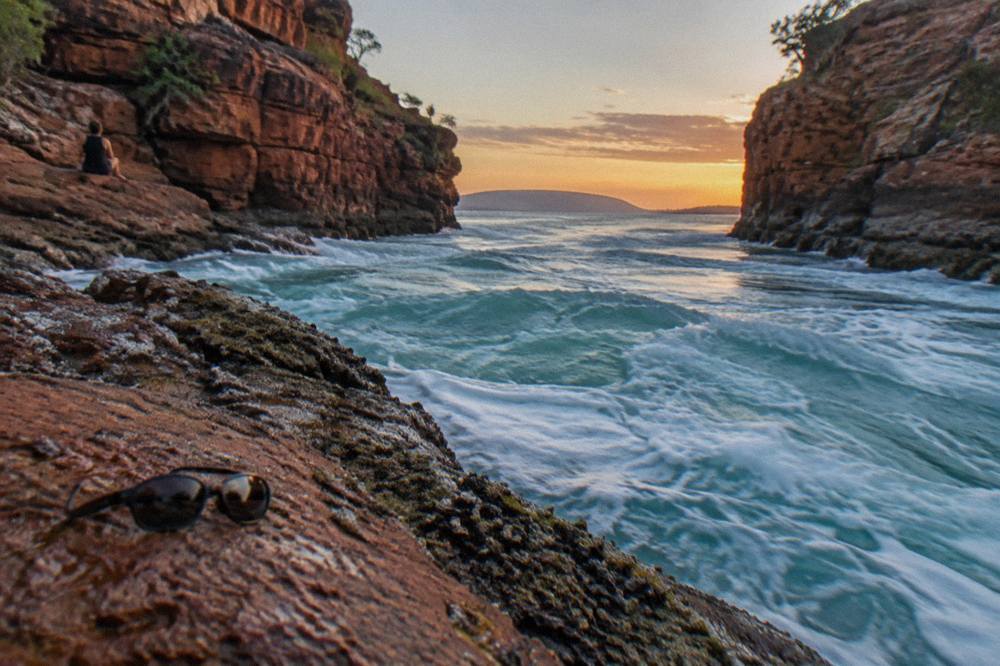 Turquoise water rushing through a narrow red rock channel between steep cliffs