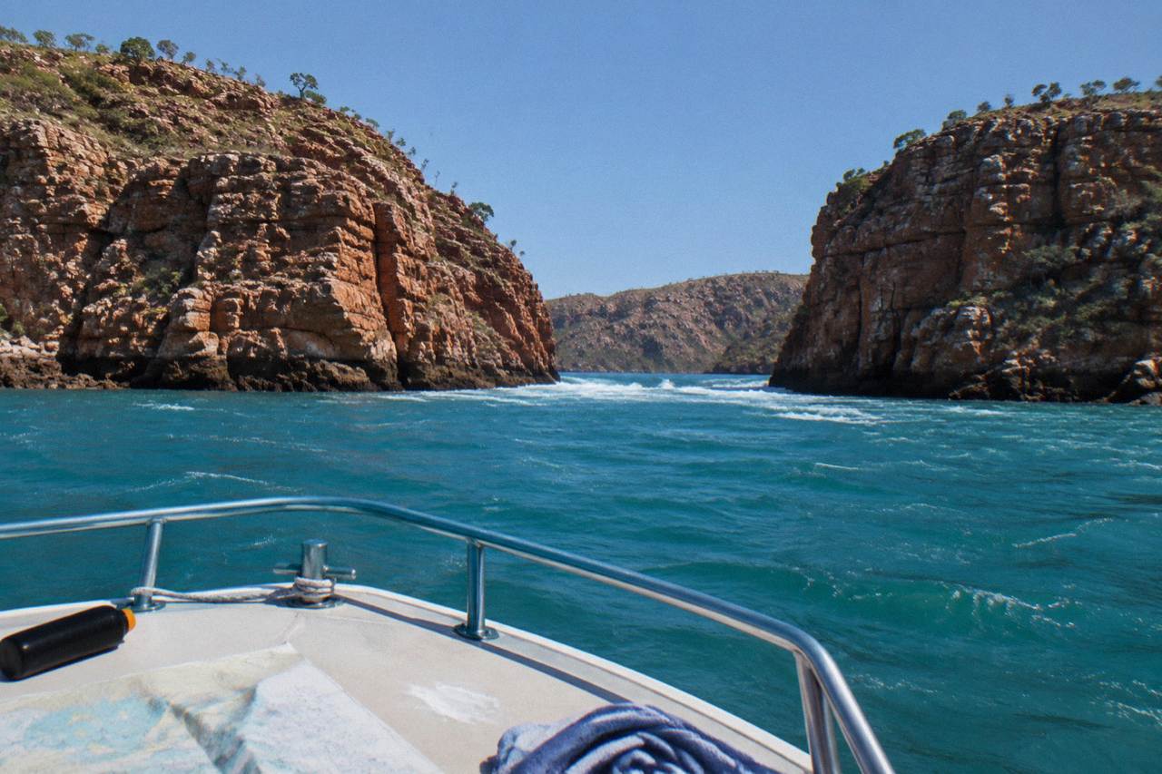 Red rock cliffs rising above turquoise water in a remote Kimberley bay