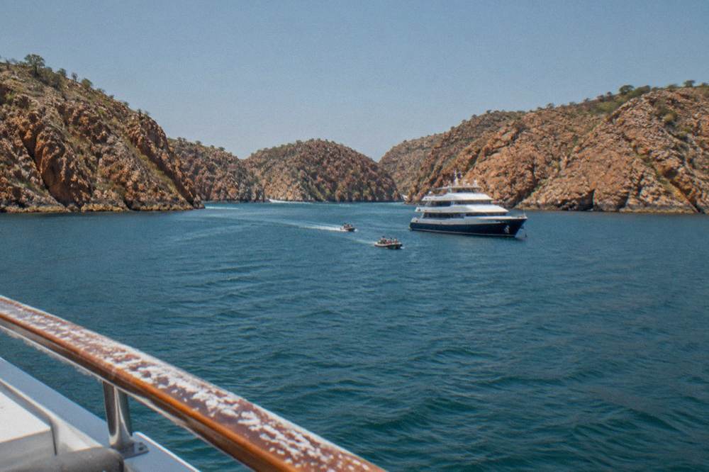 A passenger vessel anchored near rugged islands in a remote Kimberley bay