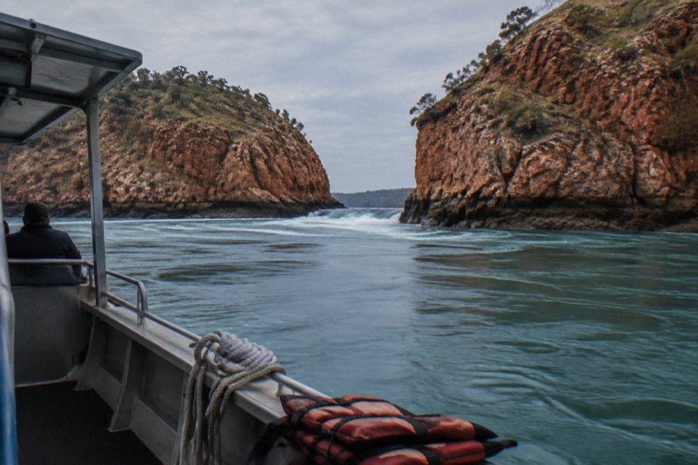 A boat holding position in open water near steep red rock cliffs at Talbot Bay