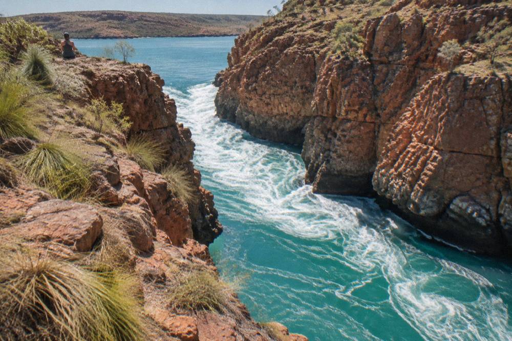 White turbulent water pouring through a rocky channel between red cliffs