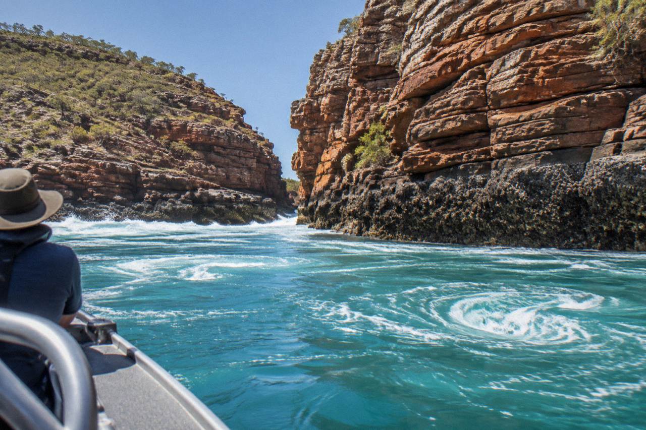 Turquoise water rushing through a narrow coastal gorge in Talbot Bay