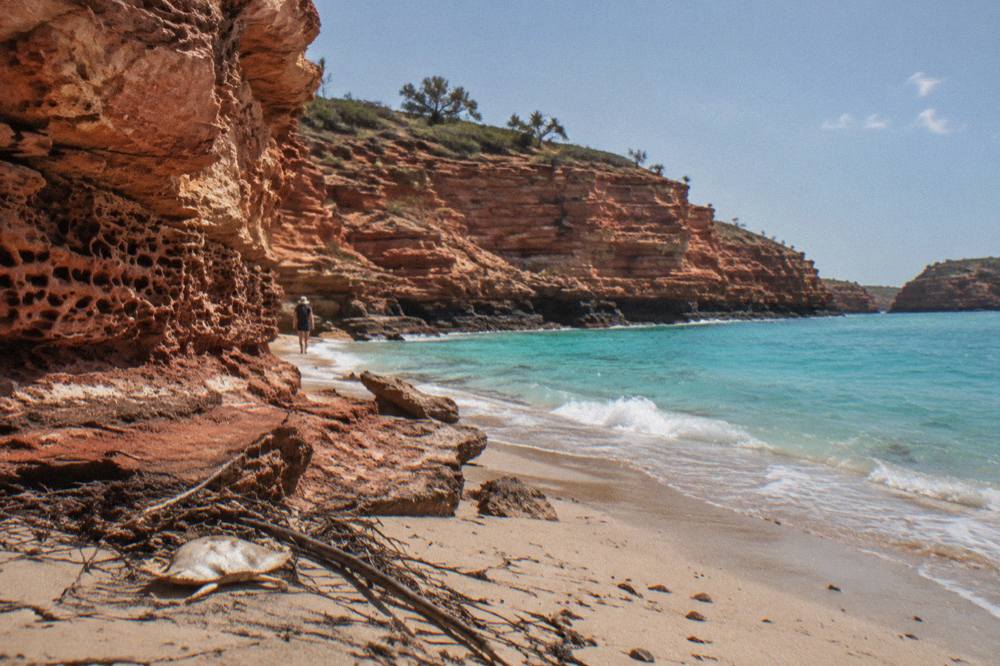 Red sandstone cliffs at a rocky point meeting a turquoise sea