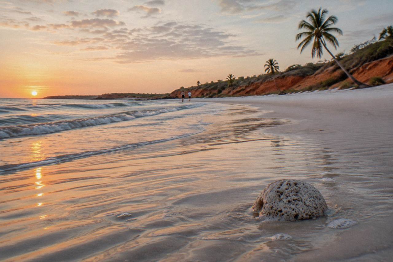 White sand beach at sunset with gentle waves along a wide tropical shore