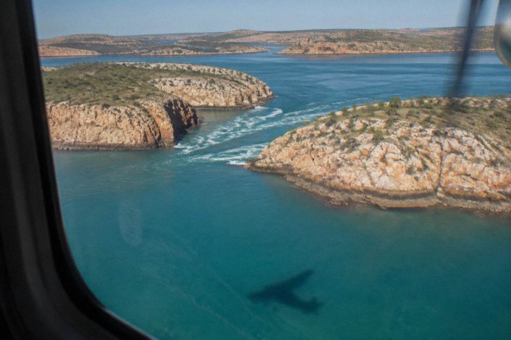 A light aircraft flying over turquoise water and scattered rocky islands