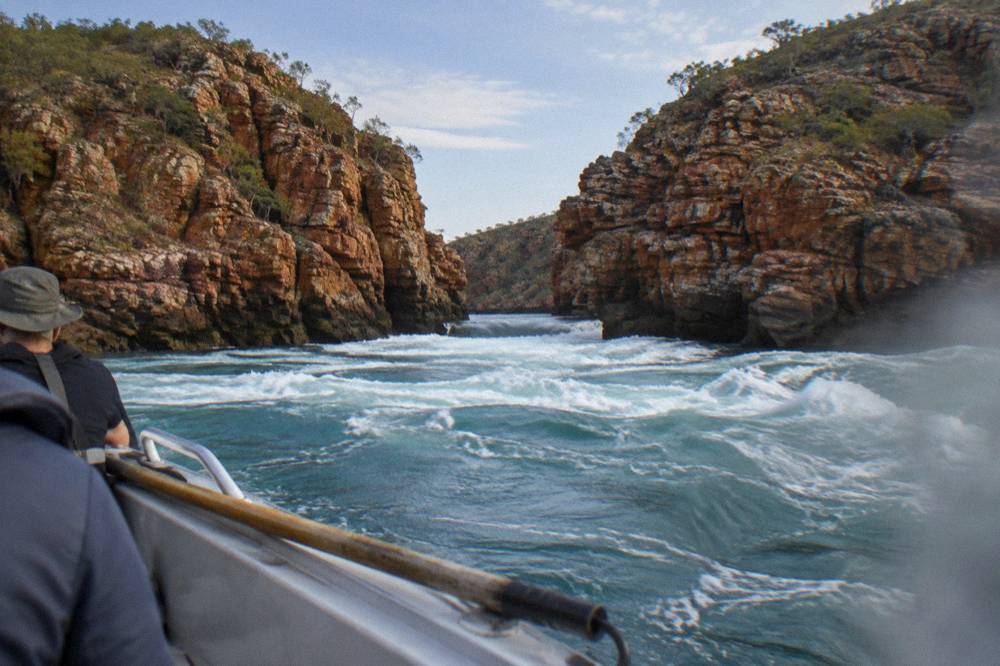 White water churning through a narrow rocky channel between red Kimberley cliffs