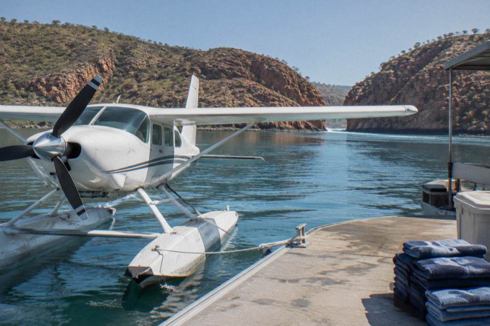 A seaplane moored beside a floating pontoon in a remote Kimberley bay