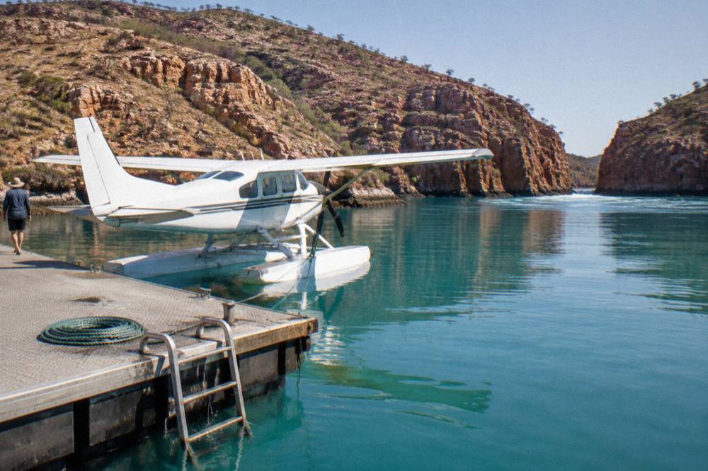 A floatplane resting on calm turquoise water beside a pontoon in a remote bay