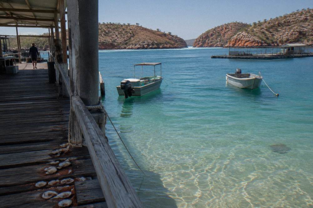 Pearl farm jetty and turquoise shallows at a remote peninsula bay dotted with boats