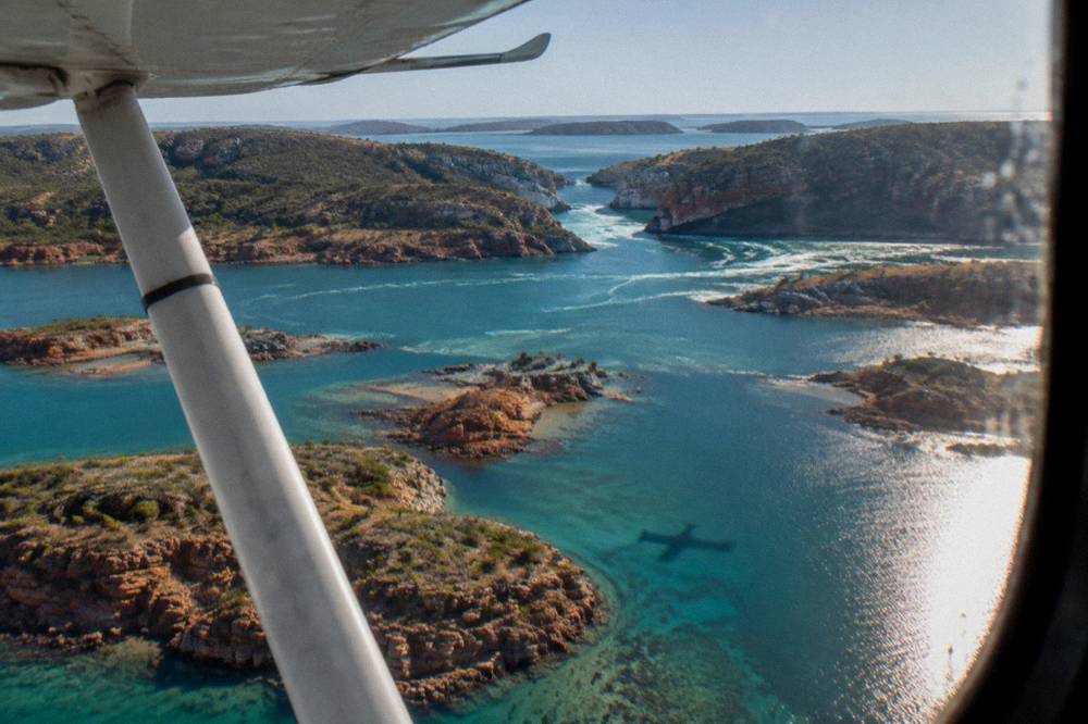 A light aircraft flying over turquoise island waters on the way to the Horizontal Falls