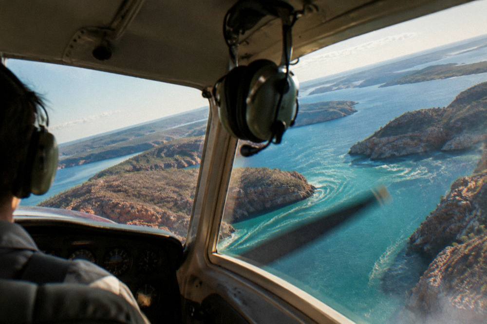 A light aircraft banking over scattered islands in turquoise sea