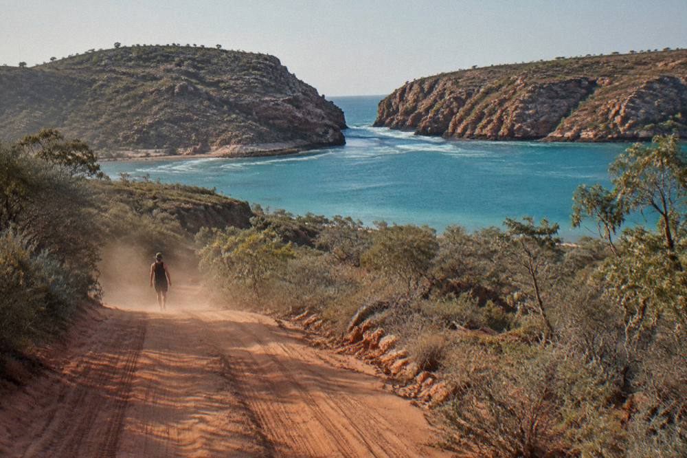 Red dirt road lined with pindan scrub leading toward the coast of the Dampier Peninsula