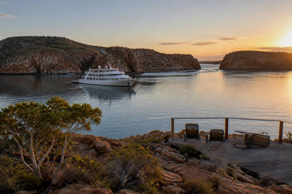 A small ship anchored between islands in a quiet bay at sunset