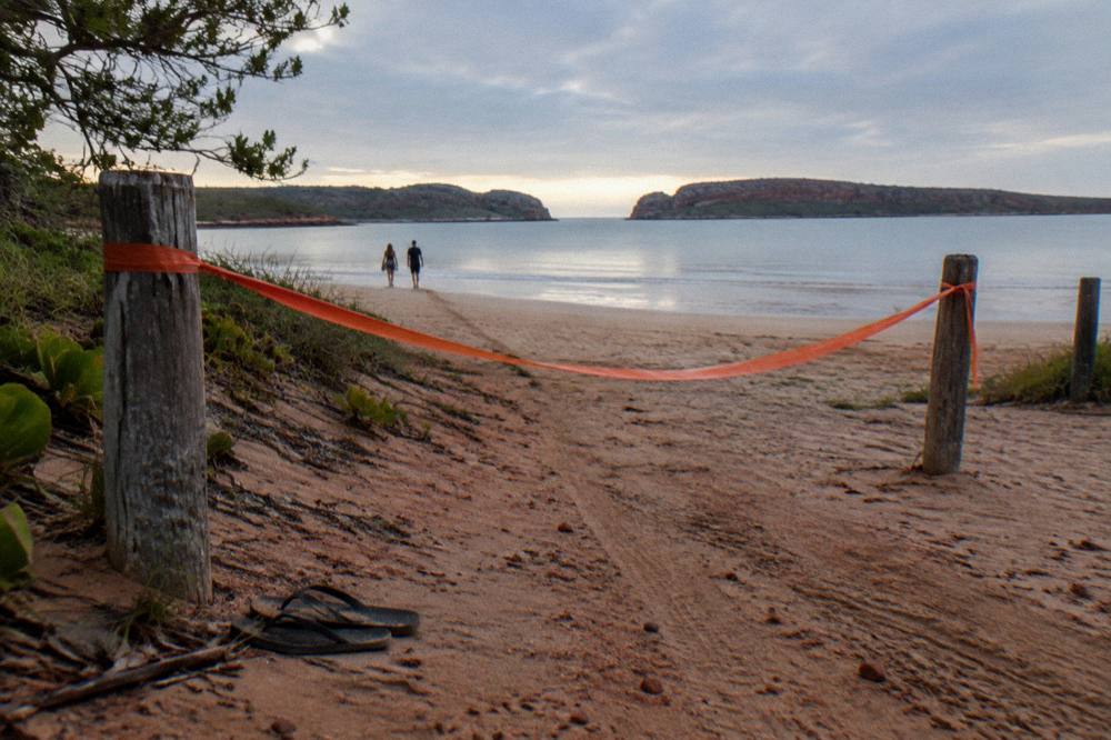 Warning sign on a beach with calm water beyond