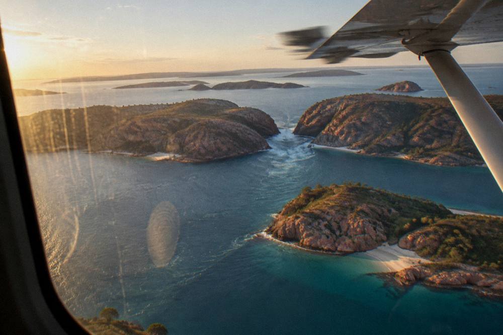 Scattered rocky islands with white sand beaches seen from a plane window over blue water
