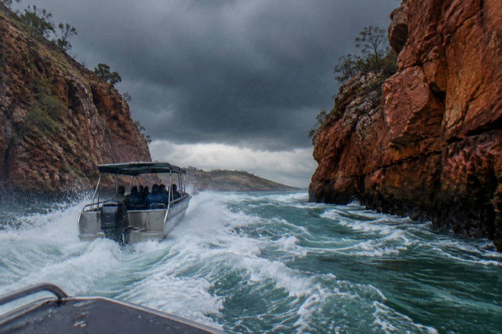 A boat cutting through white rapids between two close rock walls