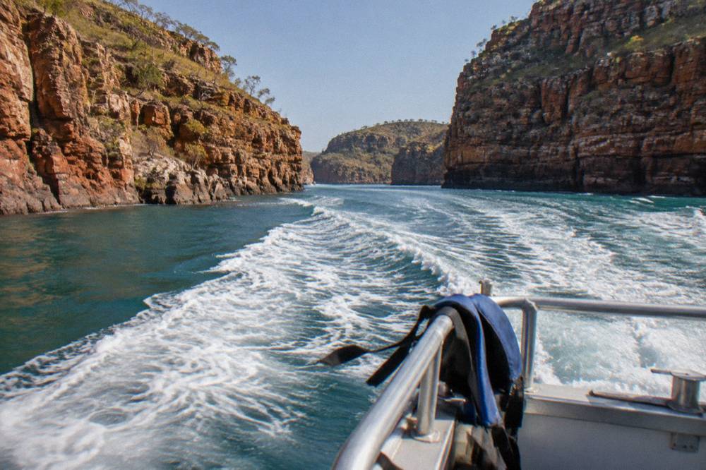 A power boat carving through white water between tall rock walls