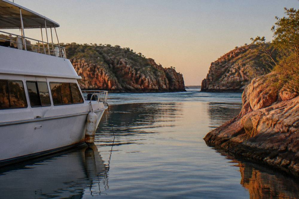A cruise boat anchored near rocky islands in calm blue water