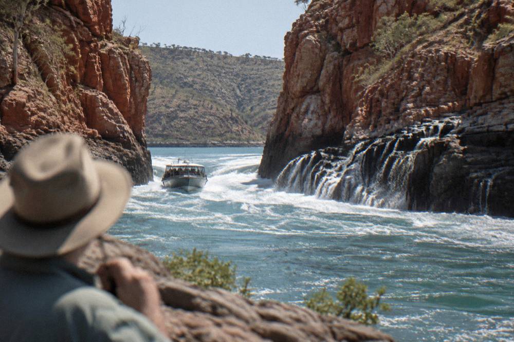 Power boat pushing through churning white water between steep rock walls