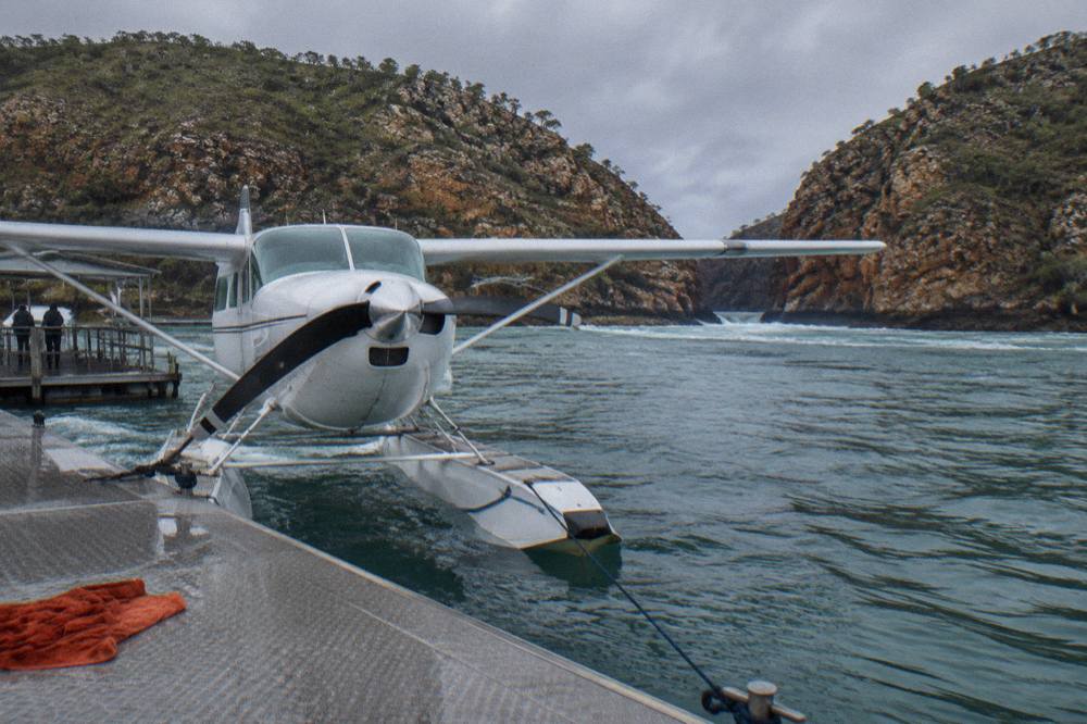 A seaplane moored beside a floating pontoon in a remote Kimberley bay