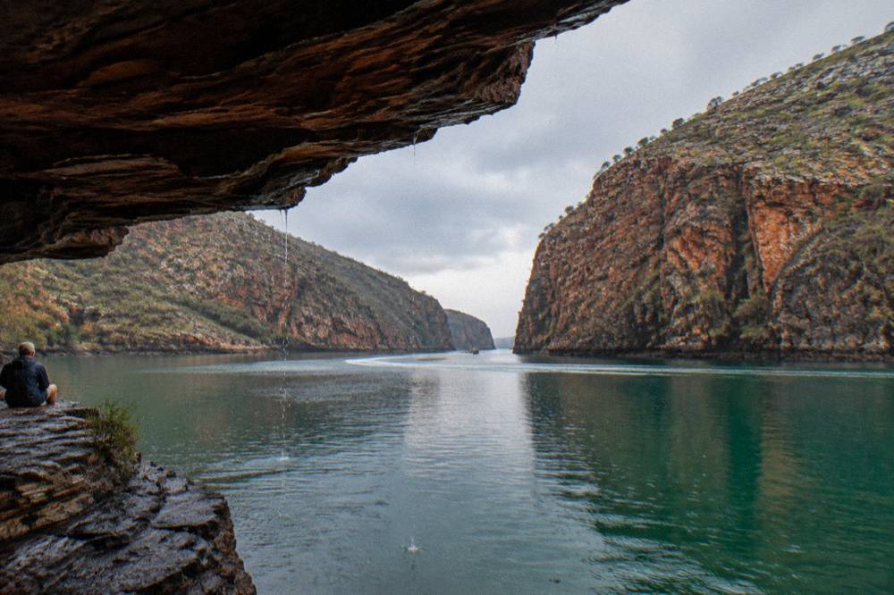 Rugged sandstone cliffs meeting clear green water in a remote bay