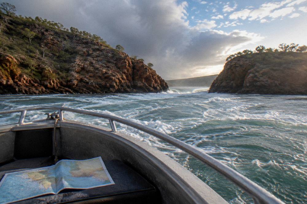 White water surging through a narrow rocky channel under a wide sky