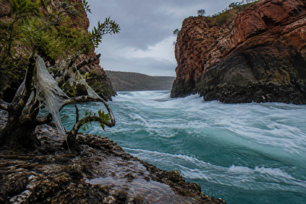 Turquoise water rushing through a narrow coastal gorge in Talbot Bay