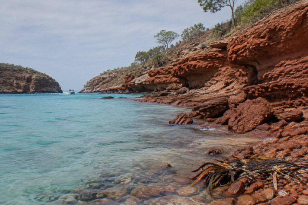 Red pindan cliffs at a coastal point above turquoise water