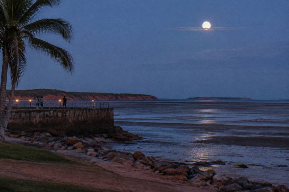 Full moon rising over exposed tidal mudflats at a sheltered bay
