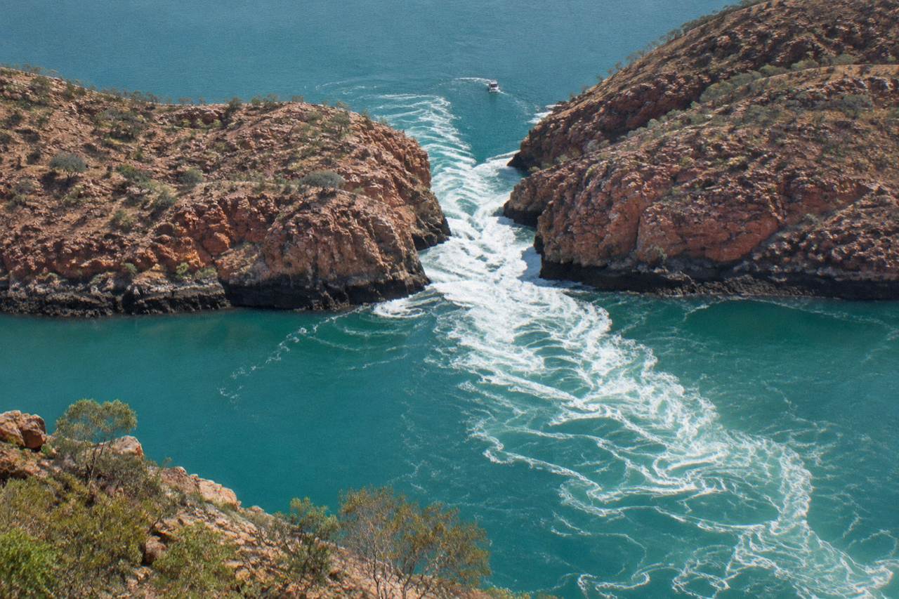Aerial view of two narrow water gaps in a red cliff range with turbulent white water between cliff walls