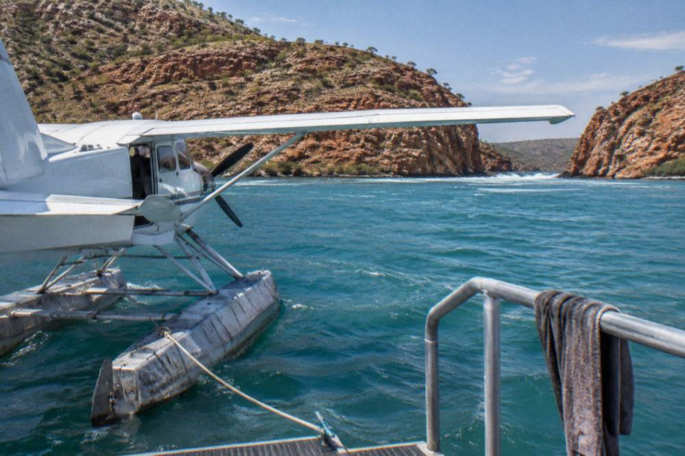 Seaplane floating on calm turquoise water beside a pontoon in a remote bay